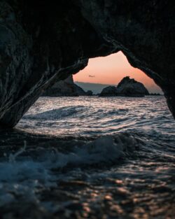 sea cave sunset ocean waves coastal cave grotto golden hour beach cliffs nature mediterranean exploration horizon tide water