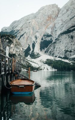 Lake Braies Dolomites wooden boat alpine lake pale mountains boathouse Italian Alps tranquil water natural landscape mountain reflection serene setting clear sky Südtirol dock summer travel