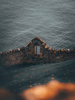 stone wall ruins window view ocean sea cliffs coastal historic ancient architecture ireland rugged heritage scenery moody serene