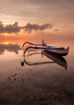 traditional boat indonesia outrigger calm water reflection sunset clouds pink sky ocean fishing boat peaceful tropical horizon serenity lake
