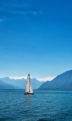 sailboat lake mountains blue serene peaceful minimal water adventure sailing alps scenic calm nature travel
