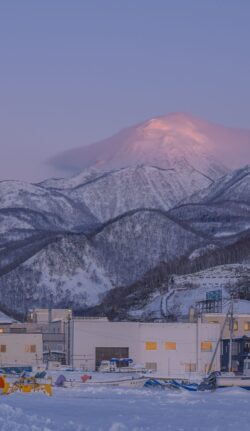 snowy mountain range winter sunrise alpenglow pastel sky town below fishing village cold weather scenic nature minimalist calm serene