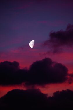 crescent moon dramatic sunset dark clouds purple sky red clouds twilight celestial night sky half moon magenta hues moody atmosphere evening sky silhouette clouds astronomy nocturnal scene