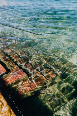 clearwater sea ocean pool rocks texture steps sunlight reflections summer vibrant beach vacation detail