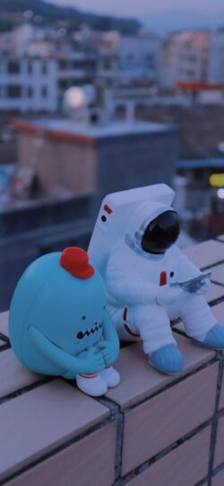 astronaut toy figurine character urban evening rooftop miniature space blue mood cityscape twilight cute collectible lifestyle