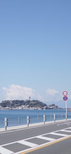coastal road Enoshima island blue sky Shonan area white clouds seaside town clear weather traffic sign 50 highway railing harbor view scenic route Japanese coastline lighthouse on hill water and la