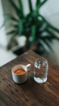 espresso shot coffee water glass wooden table cafe clean simple lifestyle interior plant background morning routine minimal aesthetic