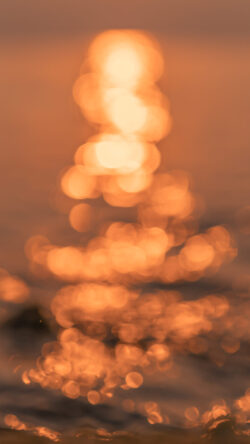 sunset bokeh blurred lights golden water abstract reflection orange shimmer sun glare out of focus warm tones bright circles water texture evening atmosphere soft background magical light vibrant c