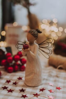 wooden angel figurine christmas decor holiday red stars ornament willow tree design soft focus bokeh cozy indoor minimal